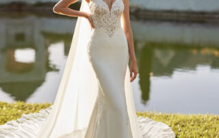 ELITA Robe de mariée en deux pièces, de coupe sirène et style sexy, confectionnée en crêpe extensible rehaussée de dentelle et pierreries. Un décolleté profond, décolleté en V et cape en georgette, ce modèle pour mariée Rosa Clará vous fera briller.