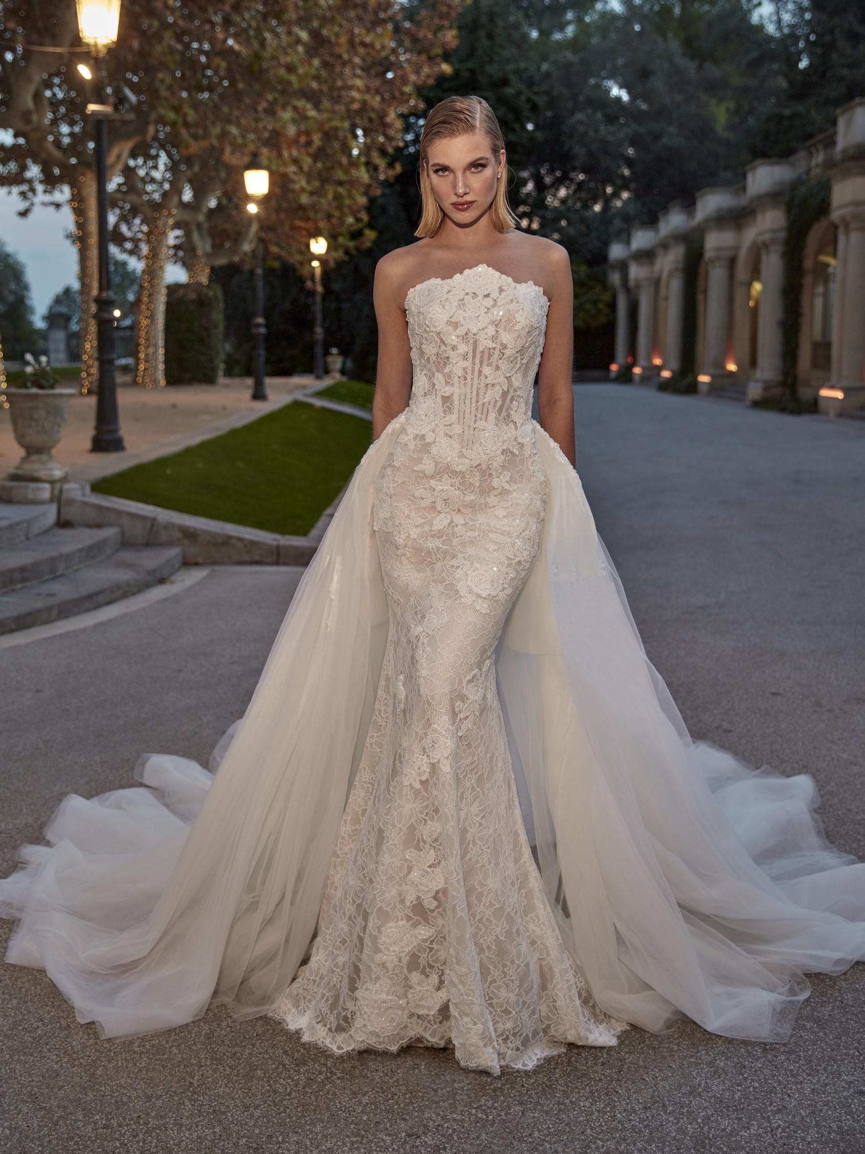 Robe de mariée Geramy – Élégance couture en dentelle et tulle Découvrez Geramy, une robe de mariée spectaculaire qui incarne le glamour et l'élégance à l’état pur. Conçue pour sublimer la silhouette, Geramy se distingue par sa coupe sirène sophistiquée et son corset bustier structuré aux détails floraux. Confectionnée dans une dentelle délicate brodée de motifs floraux, la robe épouse parfaitement les courbes avant de s’évaser dans une jupe sirène raffinée. Le corset transparent à baleines, subtilement sexy, assure maintien et structure tout en mettant en valeur la taille. La touche magique ? Une somptueuse surjupe amovible en tulle aérien, qui transforme cette robe en une véritable tenue princière pour la cérémonie. La traîne vaporeuse ajoute grâce et mouvement à chaque pas. Réservez dès maintenant votre séance d'essayage chez Signature Mariage en cliquant sur le bouton ci-dessous ou en accédant à la rubrique contact. Offrez-vous l'expérience personnalisée chez Signature Mariage pour trouver la robe de mariée parfaite qui reflète votre style et votre élégance.